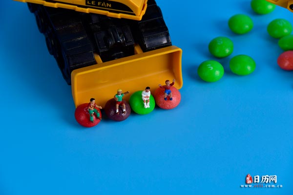 微缩摄影之坐在五颜六色糖果玩着铲车的孩子们