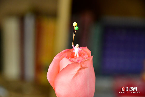 情人节微缩摄影之女孩手拿一束气球站在玫瑰花中